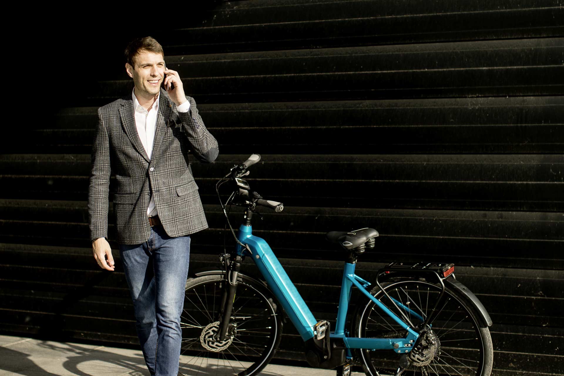 handsome-young-businessman-walks-from-his-ebike-using-mobile-phone-Kopie-2